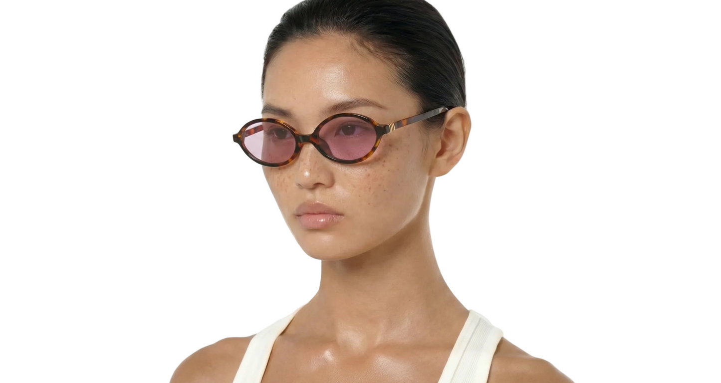 Woman wearing pink sunglasses with a plain white background